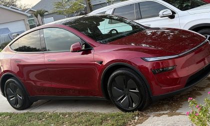 Red Tesla Model Y parked in residential driveway with suburban homes