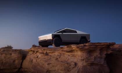 Tesla Cybertruck seen from above on rocky desert terrain near a canyon edge.