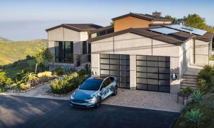 Tesla Model X parked in a modern hillside home driveway with solar panels and home EV charging station