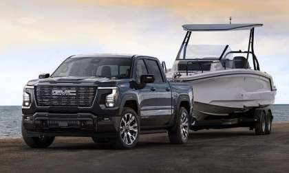 The exterior shot of the 2027 GMC Sierra 1500 Denali Ultimate in Dark Ridge Metallic towing a boat.