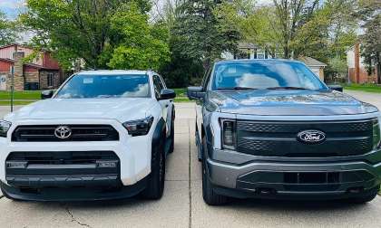 Toyota Tacoma and Ford F-150 Lightning parked side by side in a driveway for size comparison.