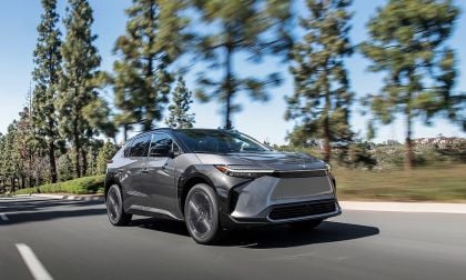 Gray Toyota bZ4X electric SUV driving on a city road with trees and motion blur