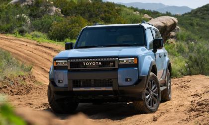 2026 Toyota Land Cruiser heritage blue driving on dirt trail through rocky mountain terrain