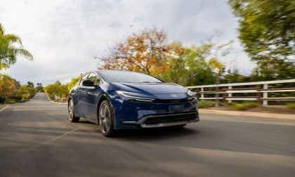 Blue Toyota Prius hybrid sedan driving on scenic road with trees