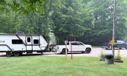 White Toyota Tundra pickup towing a white travel trailer at a wooded campground