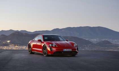 Image showing a red Porsche Taycan parked on a hill top in the mountains.