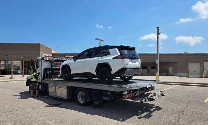 White Toyota Rav 4 being loaded onto a flatbed tow truck in a parking lot