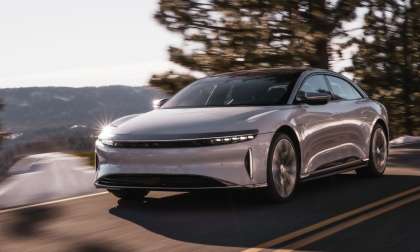 Image showing a white Lucid Air driving on a hillside road.