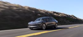 Stealth gray 2024 Tesla Model 3 electric sedan shown from a side profile in a studio environment