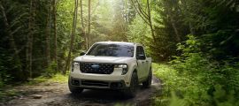 2025 Ford Maverick compact pickup driving on a forest trail, front three-quarter view