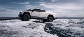 Tesla Cybertruck positioned on icy terrain, side profile view emphasizing stainless steel exterior, rugged tires, and electric truck capability in extreme conditions.