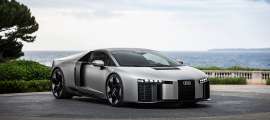 Silver Audi Nuvolari sports car parked near the coast with the ocean and cloudy sky behind it.  
