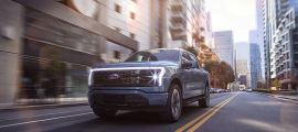 Ford F-150 Lightning electric pickup truck driving through a modern city street.