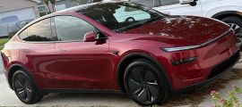 Red Tesla Model Y parked in residential driveway with suburban homes