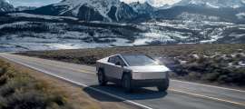 Tesla Cybertruck driving on a mountain road with snow-capped peaks in the background