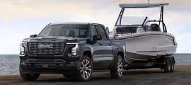 The exterior shot of the 2027 GMC Sierra 1500 Denali Ultimate in Dark Ridge Metallic towing a boat.