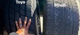 Close-up comparison of Toyo and Pirelli tire tread wear with labels on each tire.