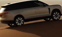 ​A side profile view of a champagne-colored NIO ES8 luxury electric SUV parked on a sandy desert dune.