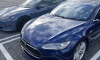 Three Tesla Model S sedans in deep blue metallic, parked side-by-side in a parking lot, showing front quarter views with distinctive LED headlights and chrome trim.