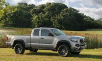 White Toyota Tacoma parked near a lake, front view of midsize pickup truck