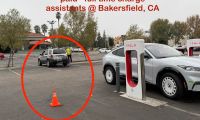 Tesla Supercharger station in Bakersfield, CA showing multiple charging stalls with a silver Tesla Model Y in the foreground, viewed from a three-quarter front angle.