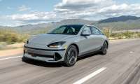 Gray 2024 Hyundai Ioniq 6 Limited driving on a desert highway with mountains in the background.