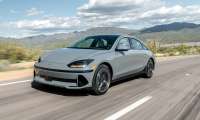 Gray 2024 Hyundai Ioniq 6 Limited driving on a desert highway with mountains in the background.