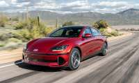 Red 2024 Hyundai Ioniq 6 Limited driving on a desert road in a front three-quarter action view.