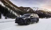 2024 Subaru Ascent driving on a snowy mountain road, shown from the front three-quarter angle.