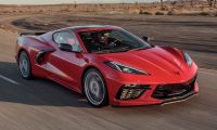 Red Chevrolet Corvette C8 driving at speed on an open desert highway, highlighting aerodynamic styling, low stance, and performance-focused front fascia.