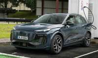 An Audi Q6 60E SUV parked at an electric charging station, plugged in and ready to charge.