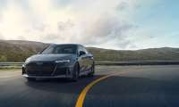 2025 Audi RS3 in dark gray, front three-quarter view, driving on mountain road with aggressive black grille and sleek LED headlights.