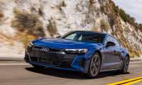 Blue Audi e-tron GT driving on mountain road with white limestone cliffs behind