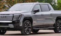 A silver 2025 GMC Sierra Denali pickup truck is shown featuring distinctive shaped LED lighting and black accents against a natural outdoor background.