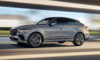 Silver Genesis GV80 SUV in motion, showcasing dynamic side profile with blurred urban background