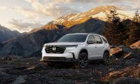 2025 Honda Pilot Black Edition SUV parked on a rocky mountain overlook with snow capped peaks behind it