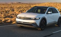 Hyundai IONIQ 5 electric SUV driving on an open desert highway, showcasing modern exterior design, LED headlights, and aerodynamic profile