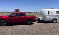 Red Ford Maverick towing a small Casita travel trailer in a full side view.