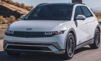 White 2025 Hyundai Ioniq 5 Limited driving on a desert highway in a front three-quarter action view.