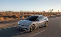 Gray 2025 Kia EV6 driving on a desert highway in a front three-quarter action view.