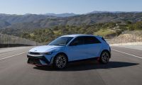 2025 Hyundai IONIQ 5 N in Performance Blue Matte on racetrack, front three-quarter view with mountains and green hills in background