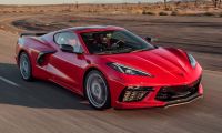 A red Chevrolet Corvette Stingray driving on a winding desert road.