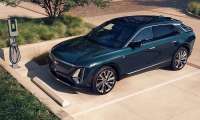 Green 2026 Cadillac Lyriq Luxury parked beside an EV charger in an overhead front three-quarter view.