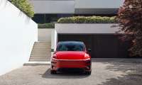 Red 2026 Tesla Model Y Performance shown from the front outside a modern home.