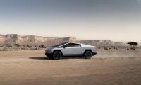 Tesla Cybertruck parked on rocky desert terrain under a clear sky