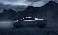 Side view of Tesla Cybertruck in a misty mountain setting, emphasizing angular stainless steel design and rugged styling.