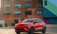 2027 Chevrolet Bolt EV red compact electric SUV front three-quarter view parked in urban setting
