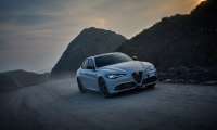 Alfa Romeo driving on misty mountain road at dramatic sunset with rocky landscape