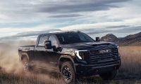GMC Sierra HD AT4X heavy duty pickup truck driving off road kicking up dust