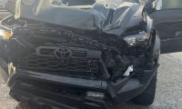 Jerry's Toyota Tacoma with severe front-end collision damage, showing a damaged grille, bumper, and hood from a front three-quarter view.